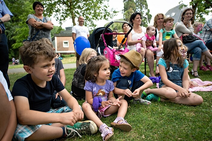 Kinder sitzen auf der Wiese im Kinderdorf und freuen sich auf den Flohmarkt.