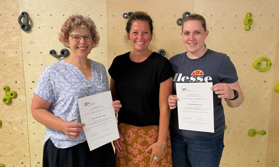 Karola Halbritter, Katja Bruysten und Denise Müller vor einer Kletterwand und mit den Prämien in den Händen