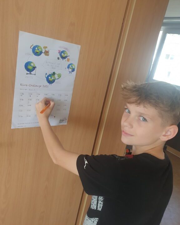 Lukas aus Haus 5 notiert die Tagespunkte auf dem Klima-Kalender