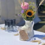 Nahaufnahme der liebevoll arrangierten Tischdeko mit Sonnenblumen und Weizen