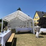 Blick in den Garten der Außenwohngruppe Rheinböllen mit aufgestelltem Zelt und Biertischgarnituren