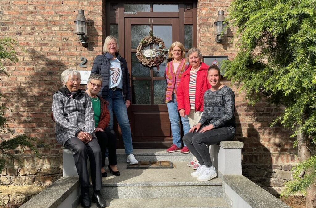 Fünf Damen der Kleiderkammer und die Gruppenleiterin der Außemwohngruppen Rheinböllen sitzen vor dem Eingang des Gebäudes