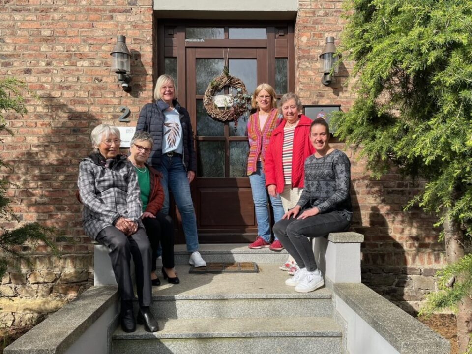 Fünf Damen der Kleiderkammer und die Gruppenleiterin der Außemwohngruppen Rheinböllen sitzen vor dem Eingang des Gebäudes