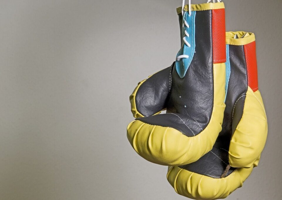 gelb-schwarze Boxhandschuhe hängen vor grauer Wand